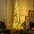 Smalt snødekt juletre med varmhvite lys i stue
