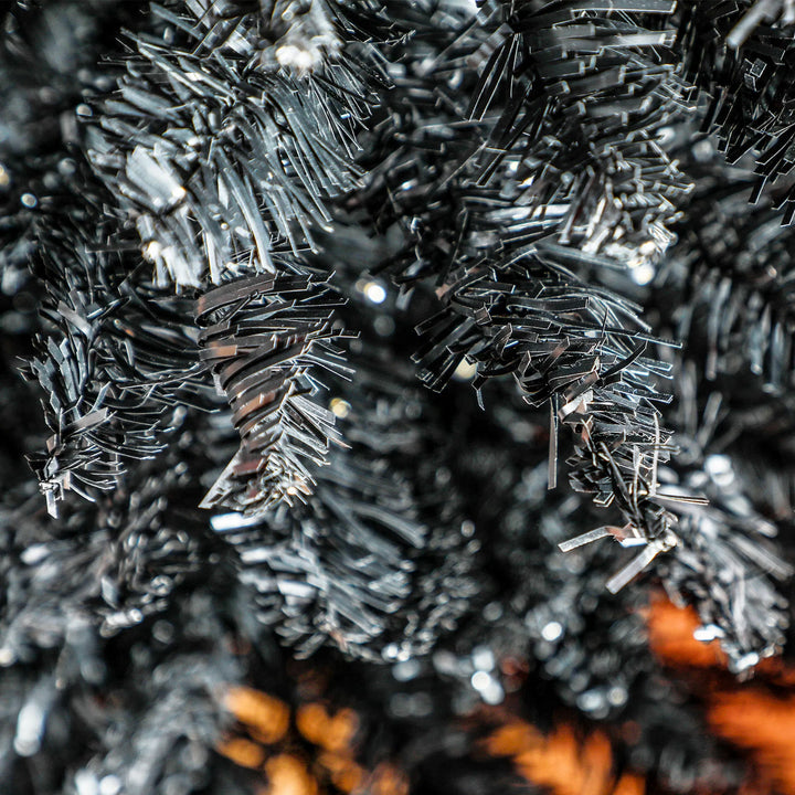 Svart smalt juletre med varme lys