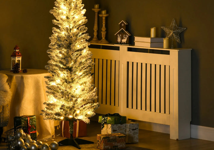 Smalt snødekt juletre med varmhvite lys i stue