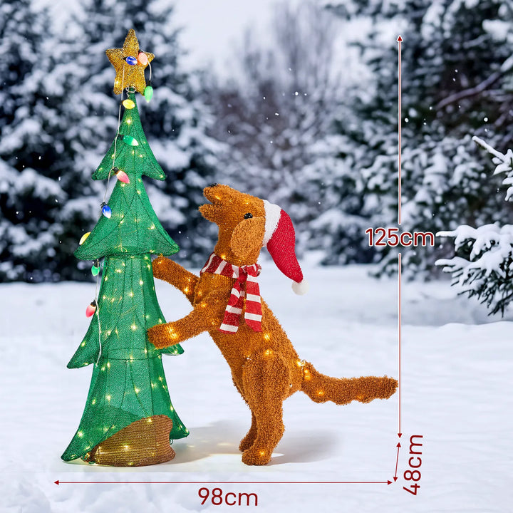 Lysende juletre med plysjhund som klatrer