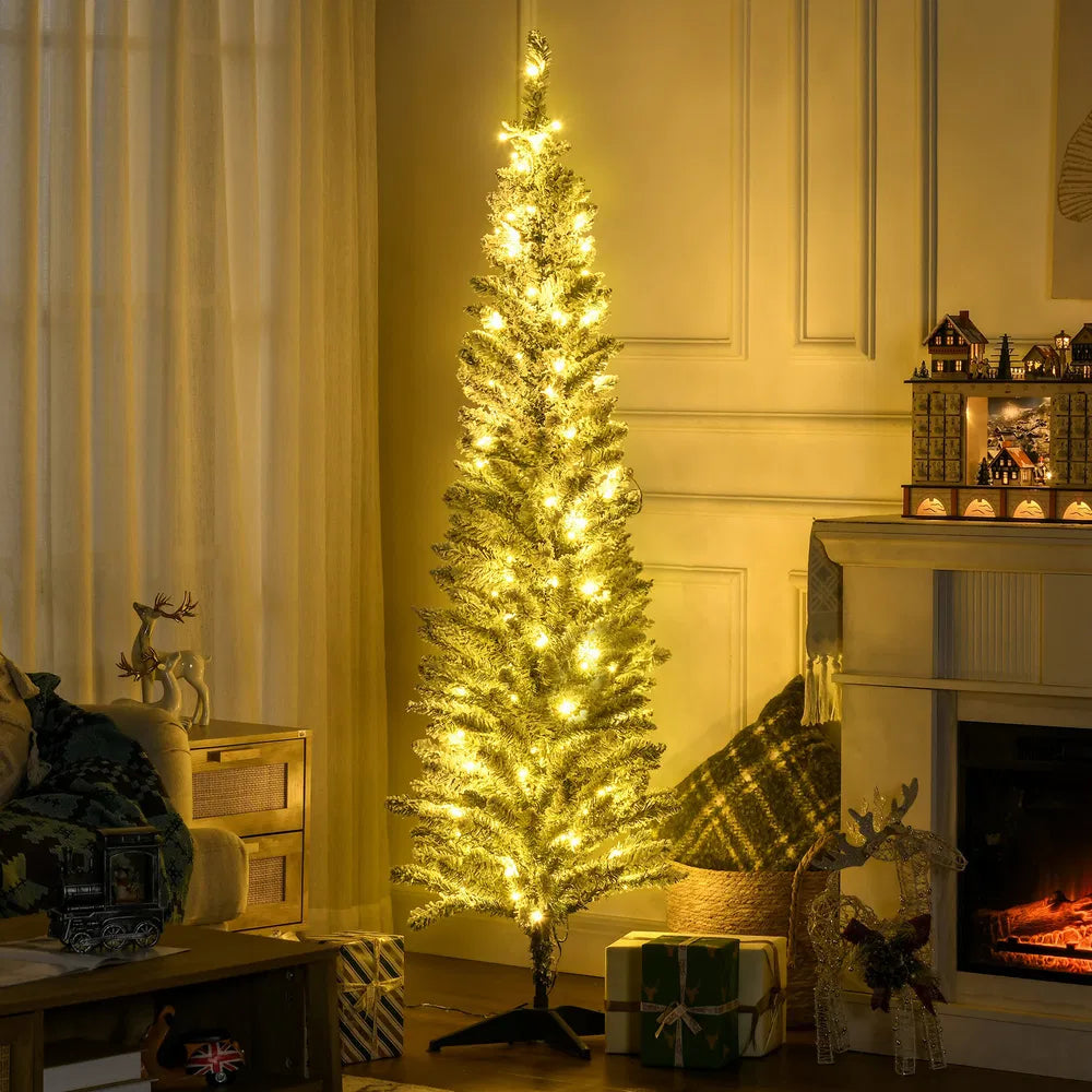 Smalt snødekt juletre med varmhvite lys i stue